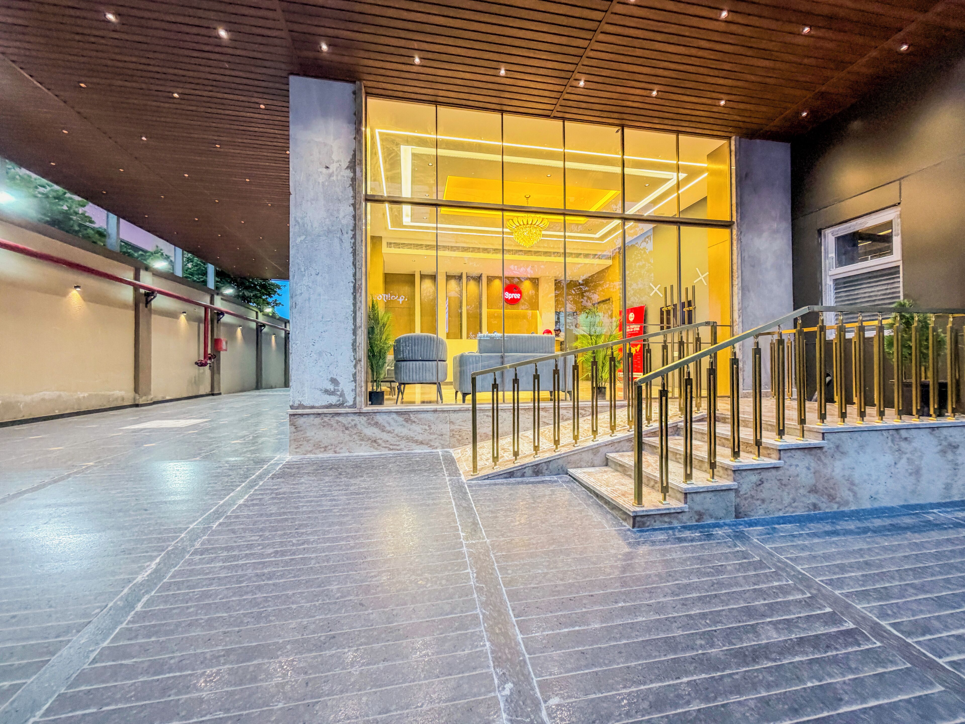 A hotel lobby with marble flooring, a staircase with metal railings, and a reception desk with chairs.