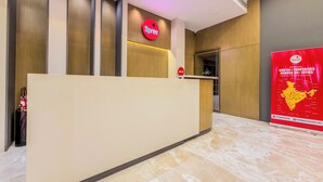 A reception desk with a Spree logo, a 'HELLO!' sign, and a Spree promotional poster. - Jain Tree by Spree Hotels Vellore (Katpadi)