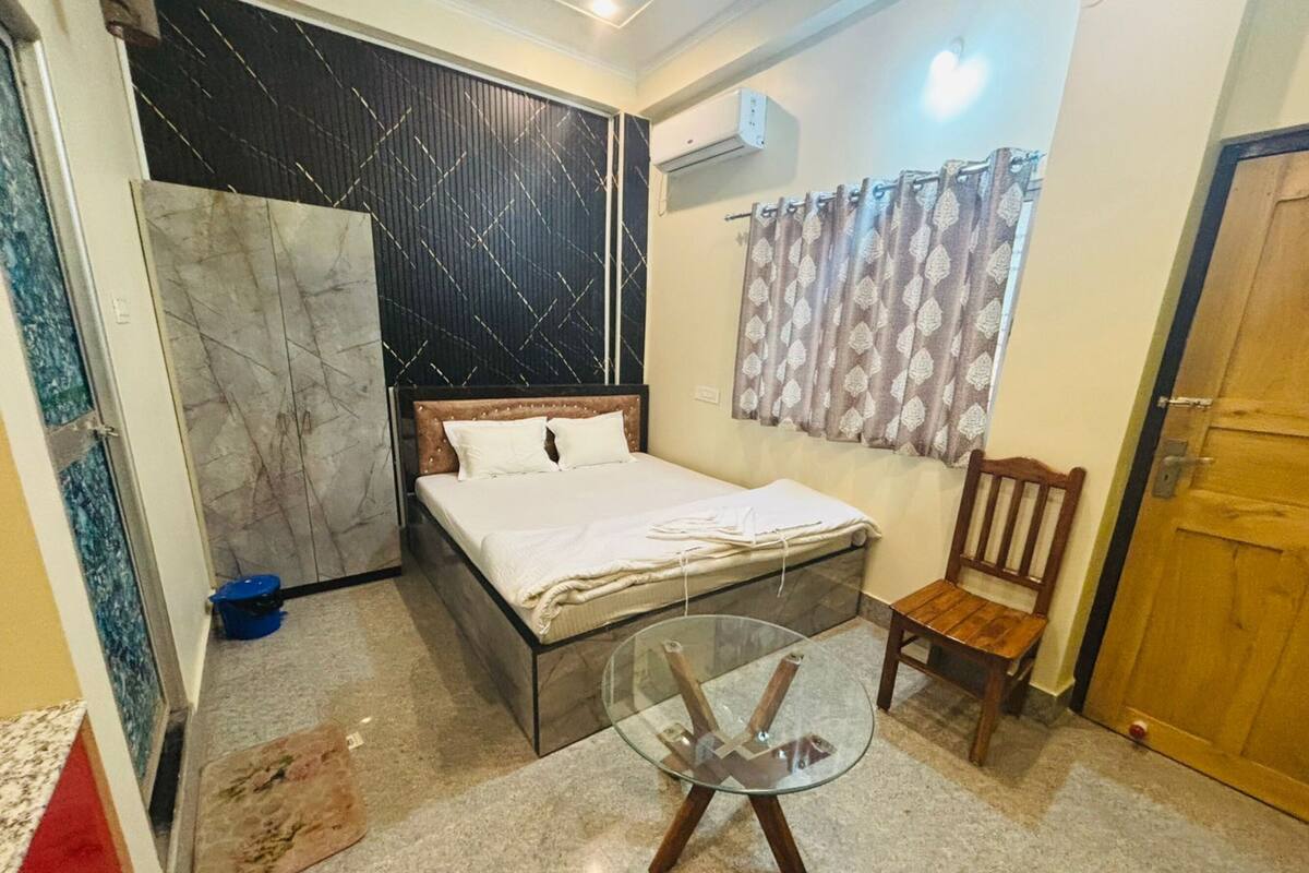 A bedroom with a bed, a glass table, a chair, a wardrobe, and a curtain.