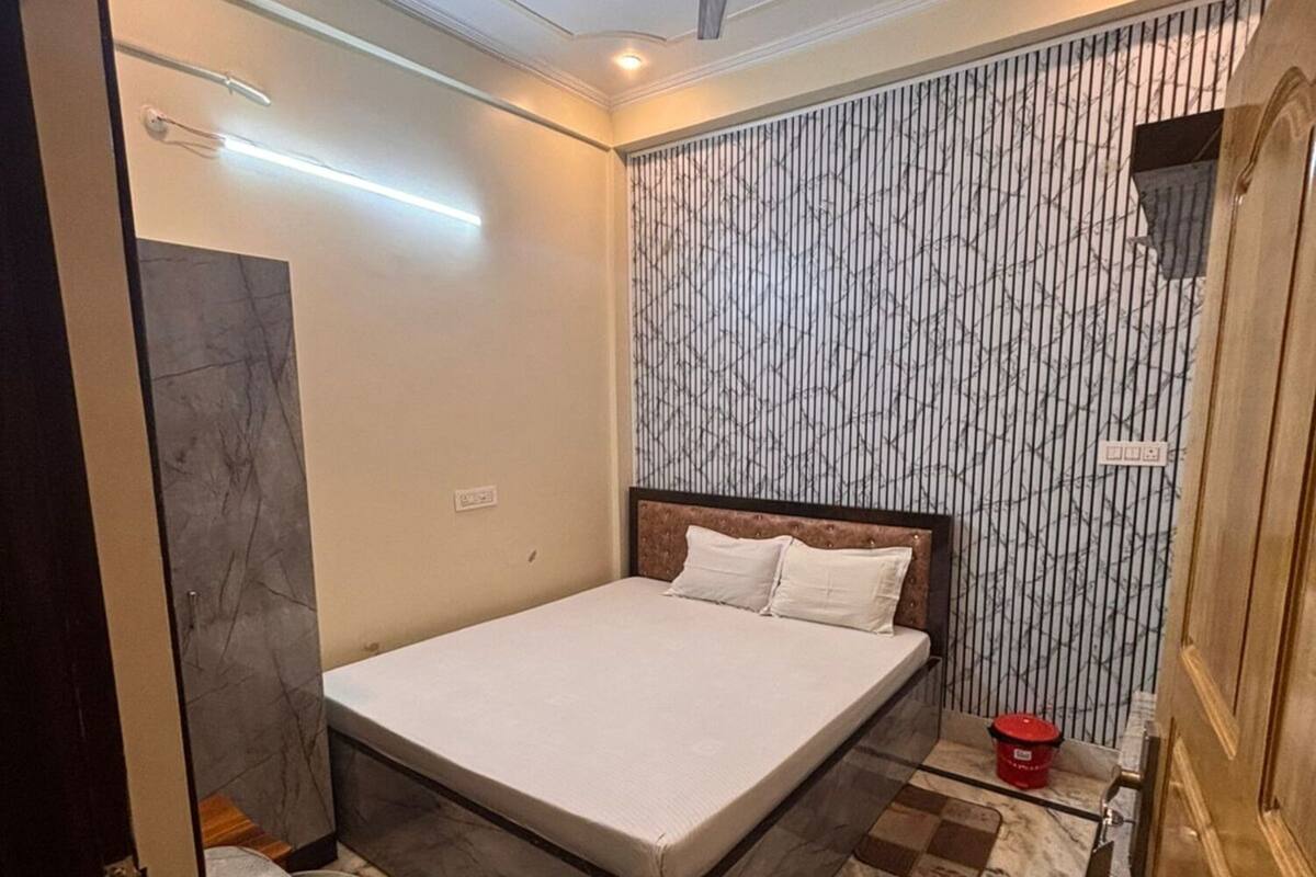 A bedroom with a bed, a ceiling fan, a marble floor, and a wall with vertical lines.