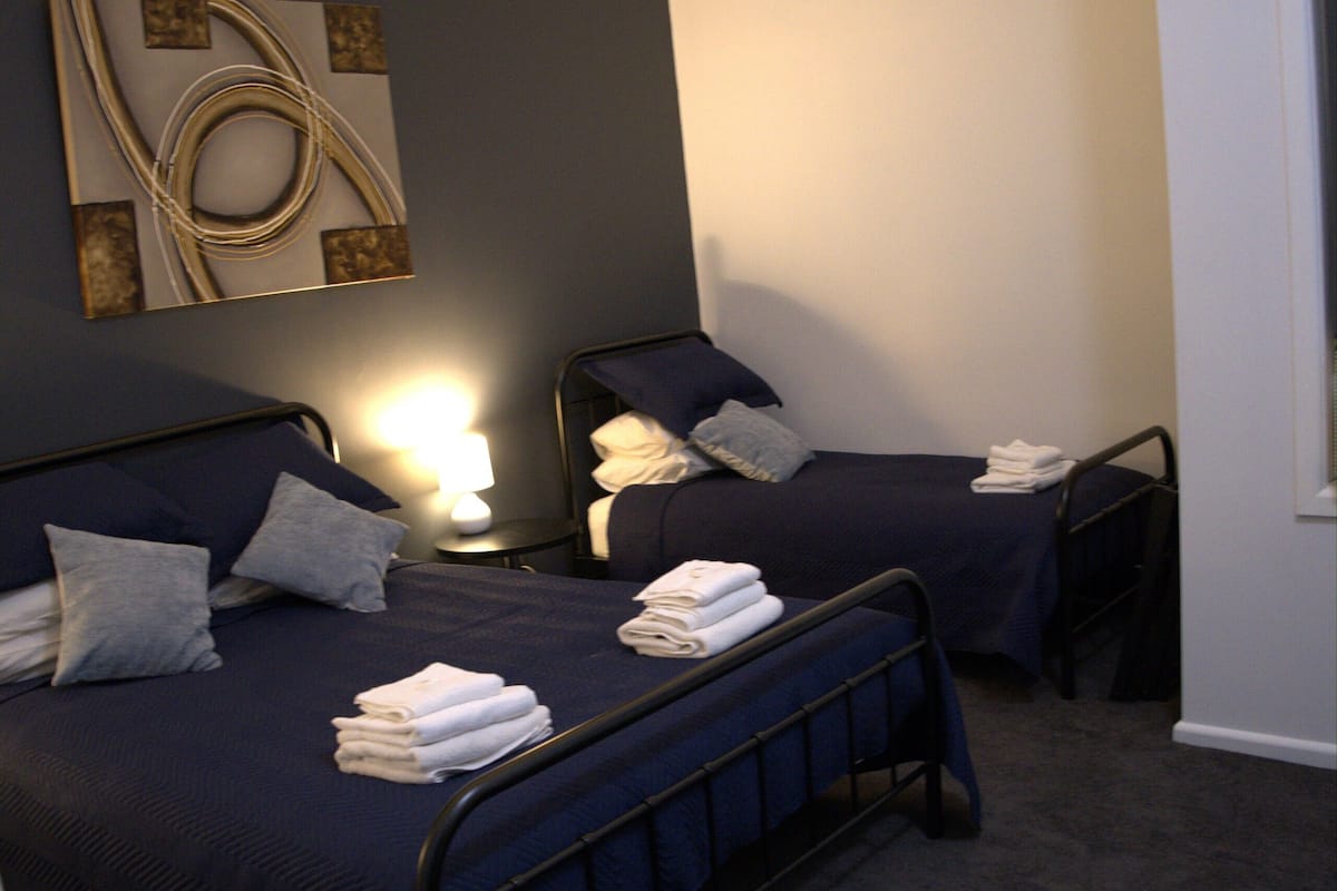 A bedroom with two beds, a wall art piece, and a lamp.