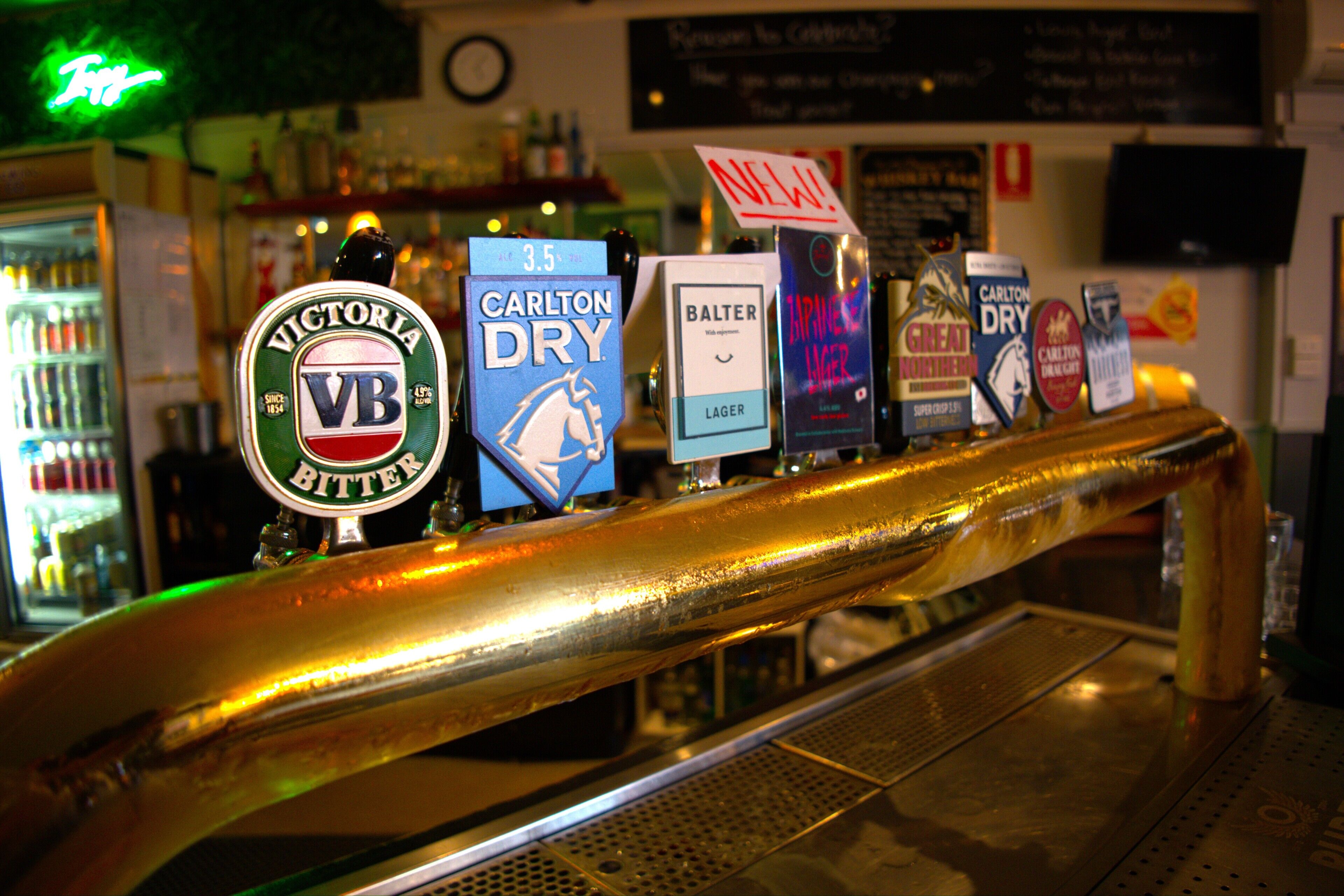 Un bar proposant un choix de bières à la pression, notamment des marques comme Victoria Bitter et Carlton Dry.