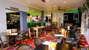 A restaurant with multiple tables and chairs, a bar area, and a sign indicating the direction to toilets. - The Imperial Hotel (Cowra)