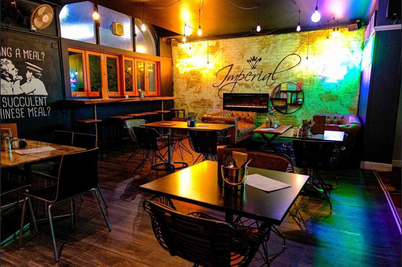 A restaurant with tables and chairs, a brick wall, and a neon sign.