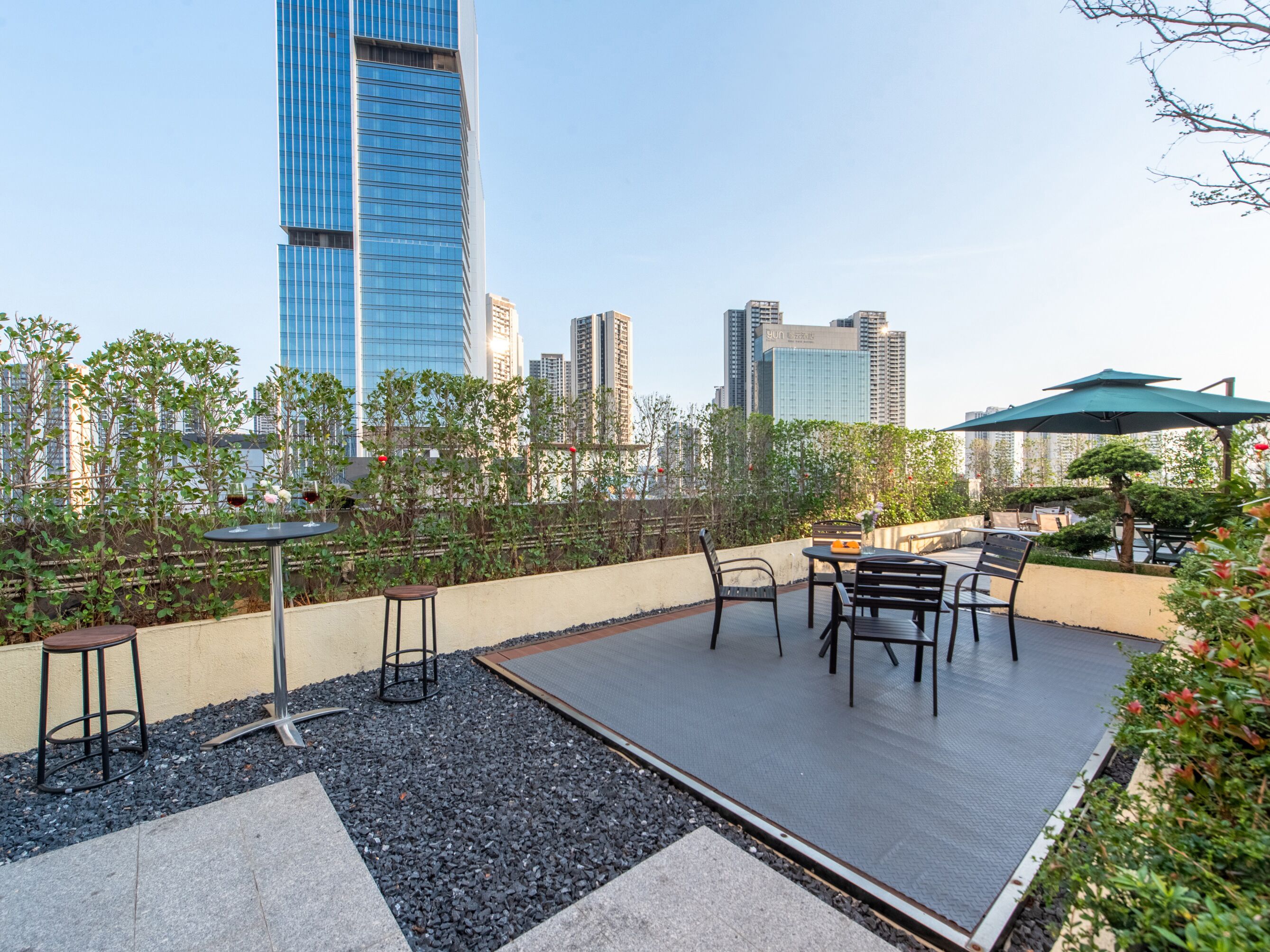 A rooftop patio with outdoor seating, a table, and a view of the city skyline.
