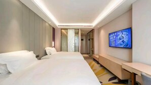 Una habitación de hotel con una cama, televisión, escritorio y espejo.