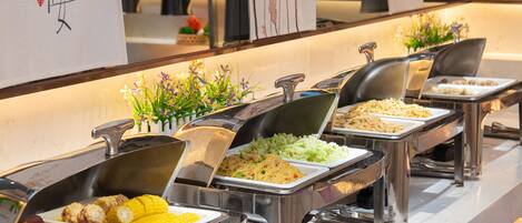 A buffet with various food options, including corn, sweet potatoes, and rice dishes.