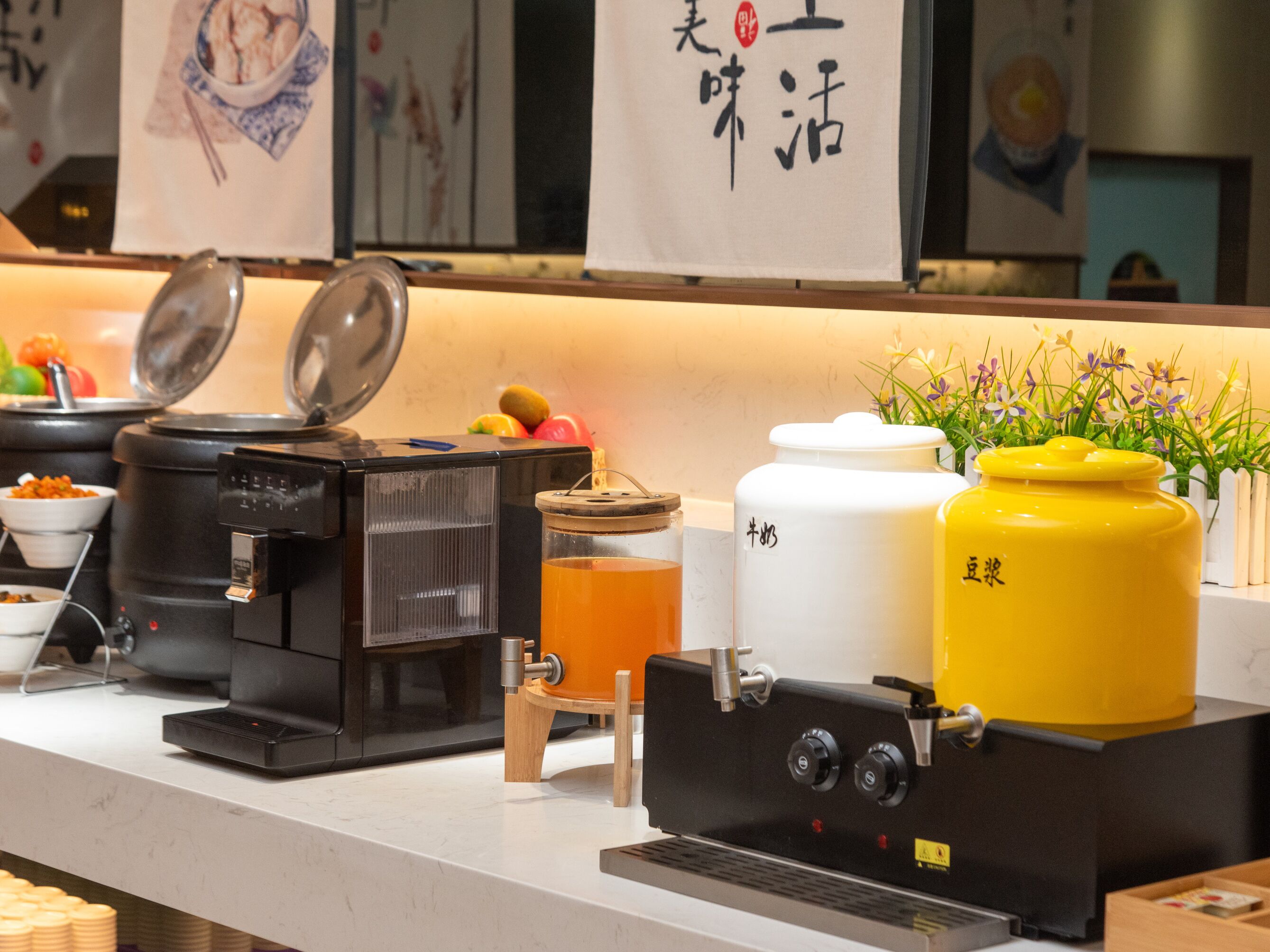 A coffee machine, a beverage dispenser, and two large containers on a counter.