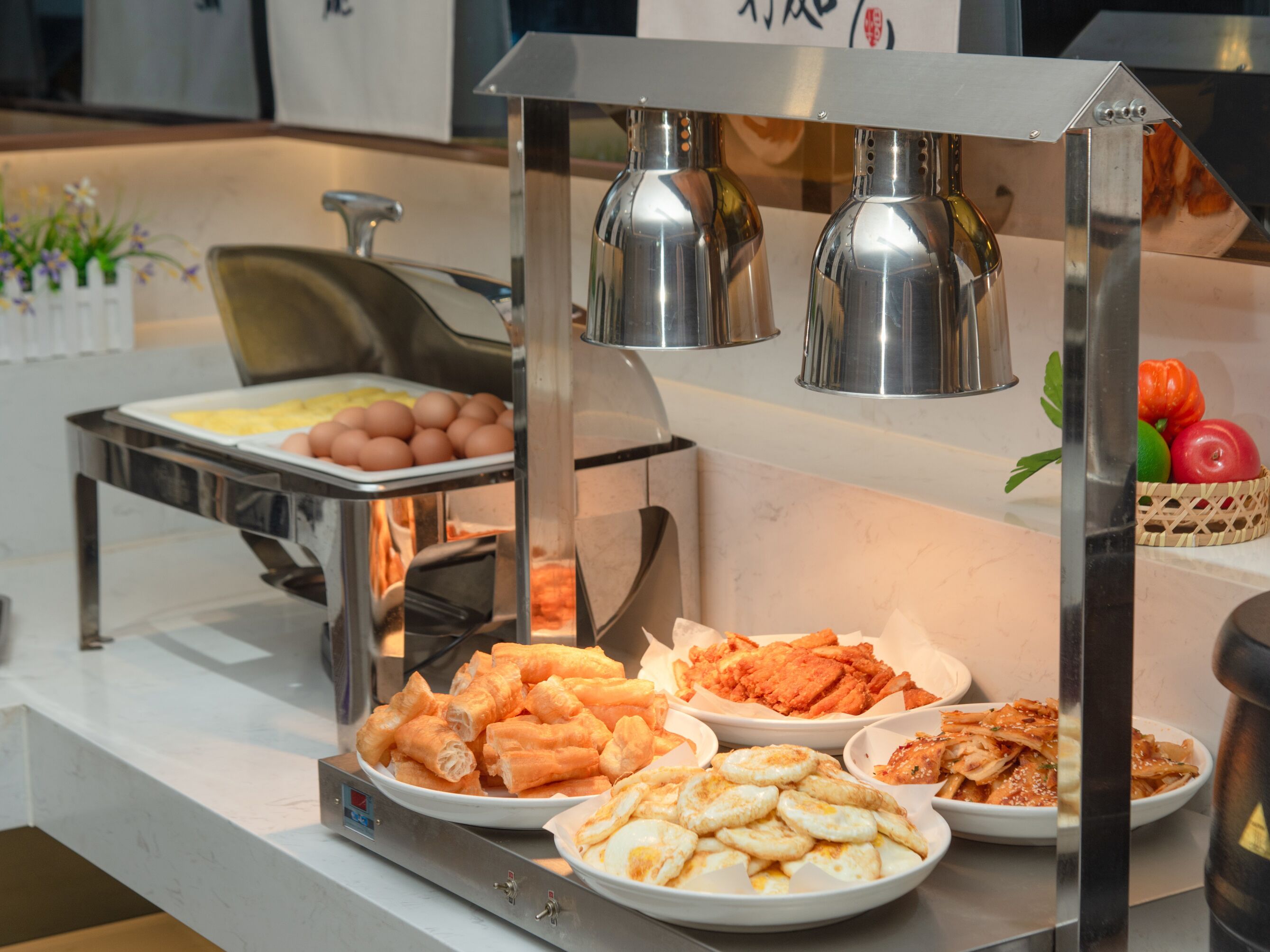 A buffet with various food items including eggs, sausages, and vegetables.