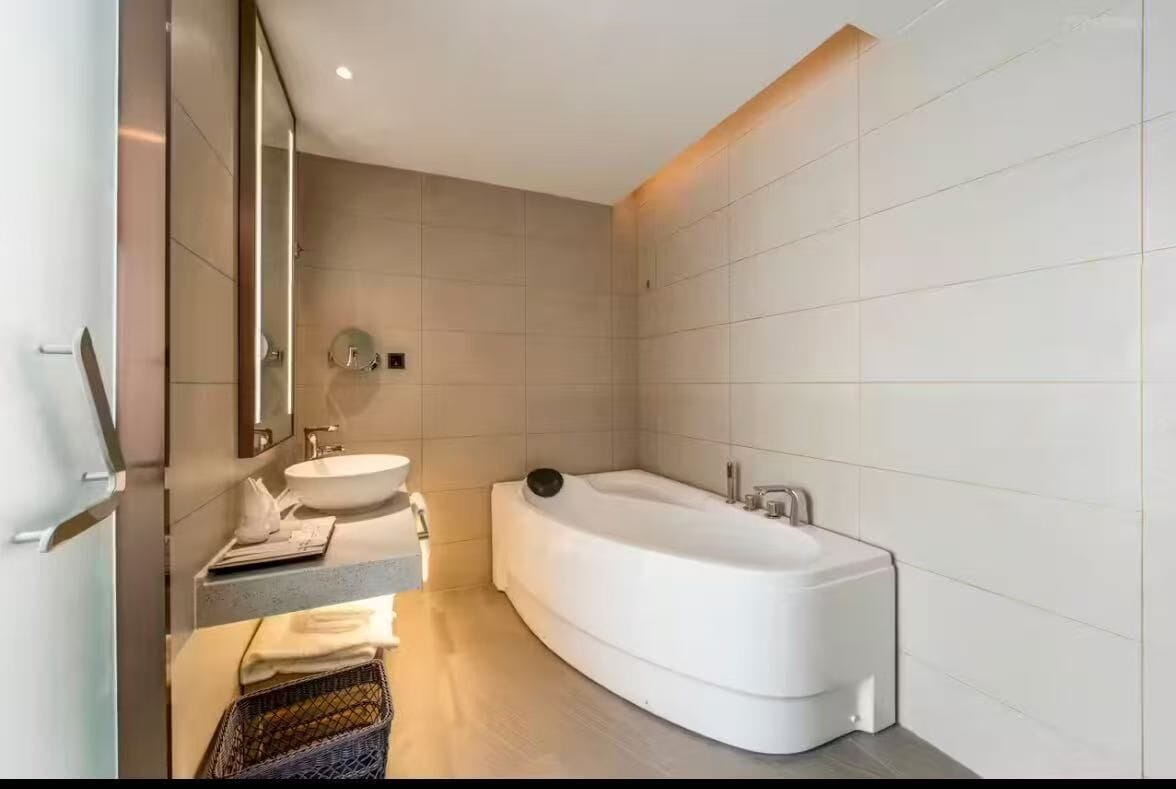 Un baño moderno con una bañera independiente, un tocador con espejo y un lavamanos.