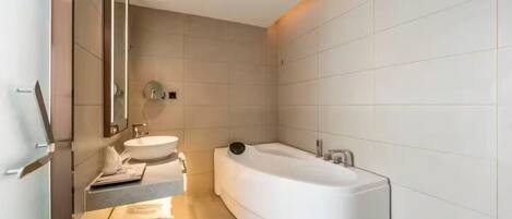 Un baño moderno con una bañera independiente, un tocador con espejo y un lavamanos.