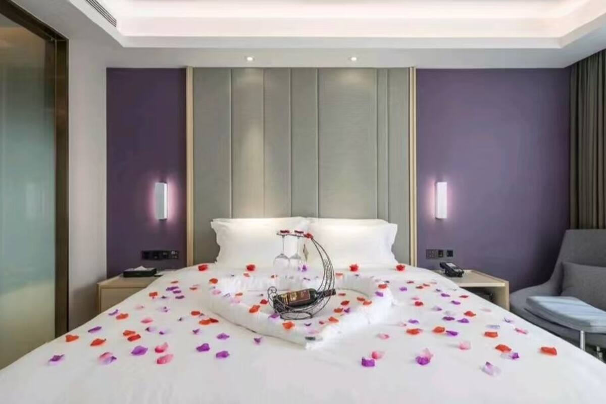 Una habitación de hotel con cama, mesitas de noche, una silla y una bandeja decorativa con flores.