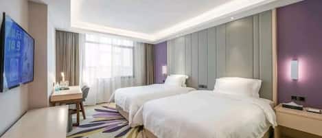 Habitación de hotel con dos camas, un escritorio, un televisor y un ventanal amplio.
