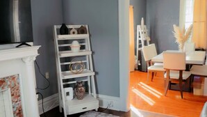 Una sala de estar con chimenea, un estante blanco, una alfombra mullida y un comedor con sillas y una mesa.
