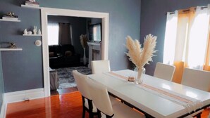 Un comedor con una mesa blanca, sillas y un jarrón con plumas de pluma.