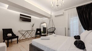 Een moderne hotelkamer met een groot bed, een bureau, een stoel, een hangstoel en een kroonluchter.