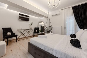 A modern hotel room with a large bed, a desk, a chair, a hanging chair, and a chandelier. - Solena Villa,Private Pool,Kids Playroom near the Beach (Stavromenos)