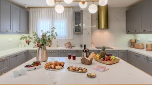 Een moderne keuken met grijze kastjes, een marmeren aanrechtblad en een centraal eiland met eten en drinken.