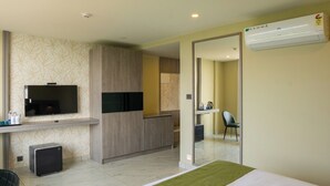 Une chambre d’hôtel équipée d’un lit, d’une télévision, d’un bureau avec un ordinateur, d’une chaise et d’un appareil de climatisation.