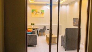 Un interior moderno con comedor, dos sofás, una pequeña mesa con un florero y obras de arte en las paredes.