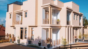 Un edificio moderno de dos pisos con balcones, ventanas amplias y un área de entrada pavimentada.