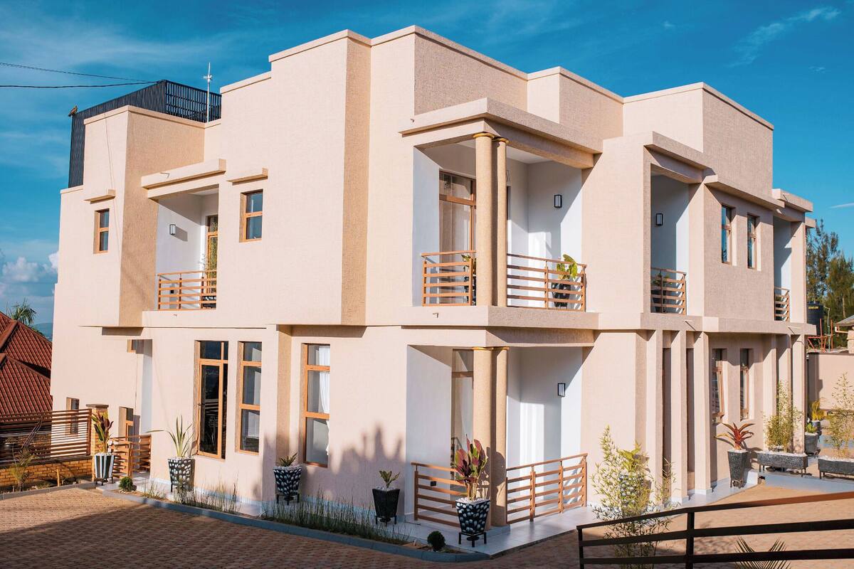 Un bâtiment moderne à deux étages, doté de balcons, de grandes fenêtres et d’un espace d’entrée pavé.
