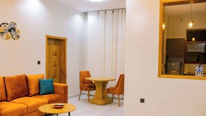 Una sala de estar moderna con un sofá, una mesa redonda de centro y un comedor con mesa y sillas.