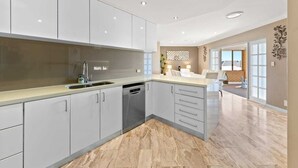 A modern kitchen with grey cabinets, a dishwasher, and a large island with a sink. - 47 Ultimate Entertainer! Pool, Man Cave, Kids Play (Stirling)