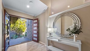 A modern interior with a large mirror, a console table, and a view of an outdoor garden. - 47 Ultimate Entertainer! Pool, Man Cave, Kids Play (Stirling)