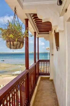 A balcony with a hanging planter, a view of the sea, and a railing. - Beytsalam (Lamu)