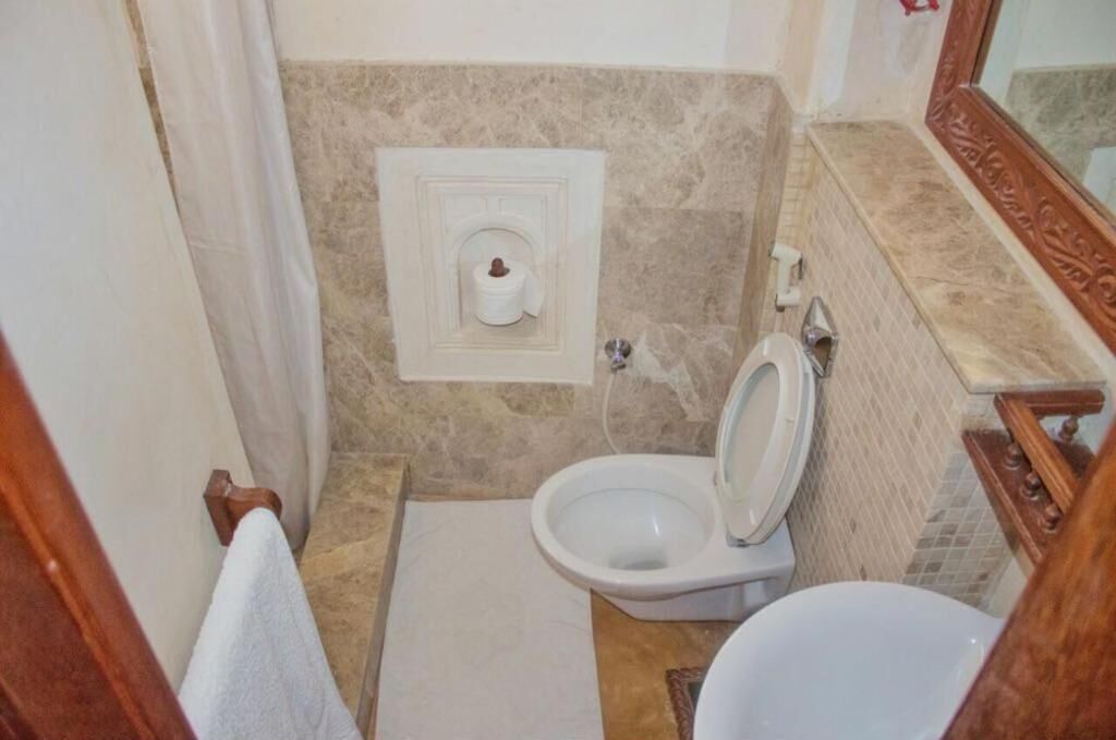 A bathroom with a toilet, a bidet, and a towel rack.