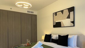Ein modernes Hotelzimmer mit einem Bett, einer grünen Decke, einem großen abstrakten Gemälde und einem Holzschrank.