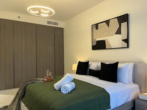 Ein modernes Hotelzimmer mit einem Bett, einer grünen Decke, einem großen abstrakten Gemälde und einem Holzschrank.