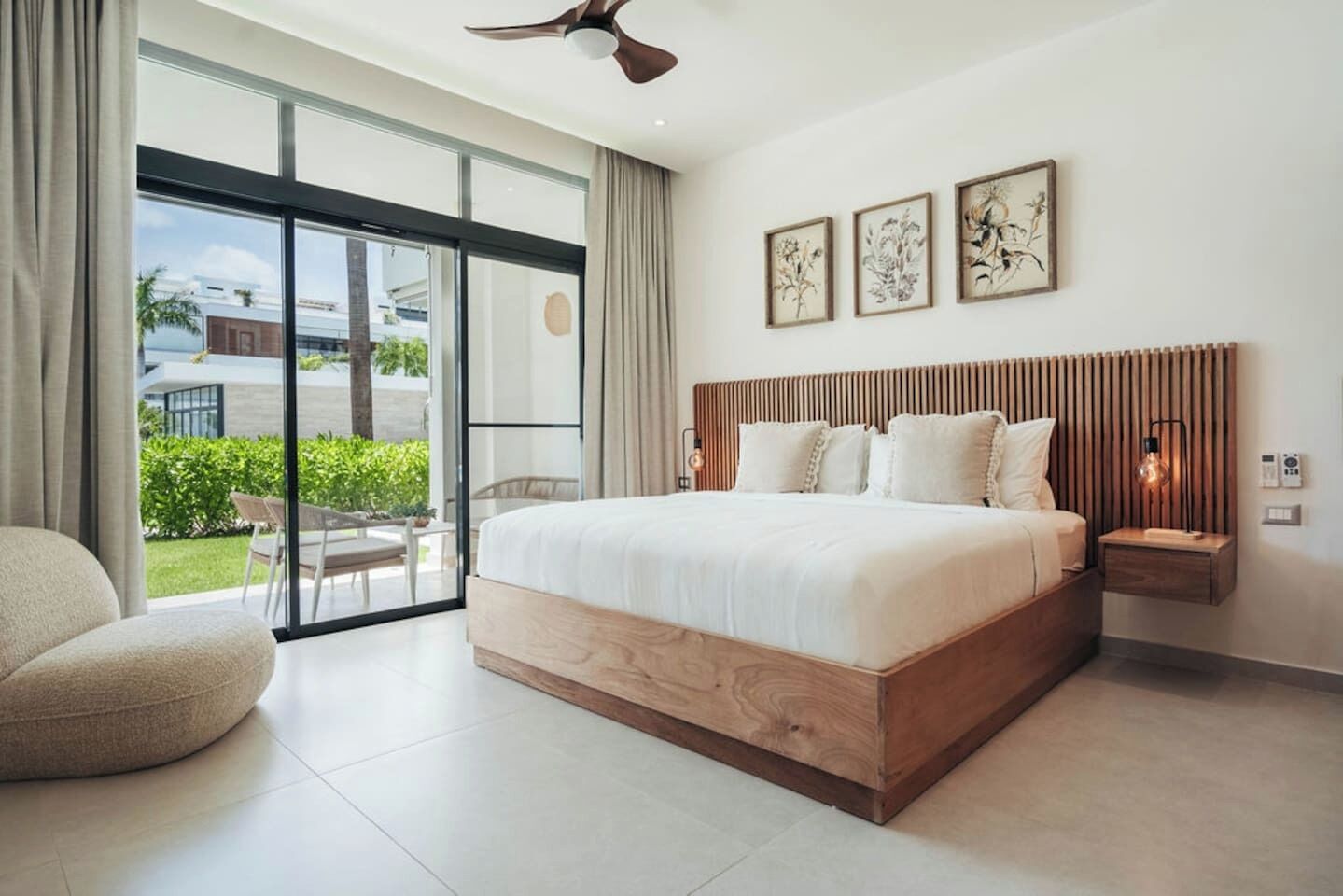A modern bedroom with a large bed, a ceiling fan, and a view of the outdoors.