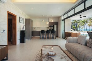 Ein modernes Wohnzimmer mit einer Couch, einem Couchtisch und Blick auf die Küche sowie den Außenbereich.