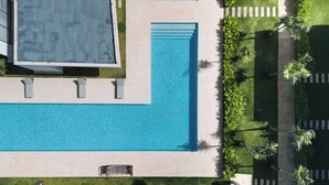 Vista aerea di una piscina circondata da un giardino e un edificio.