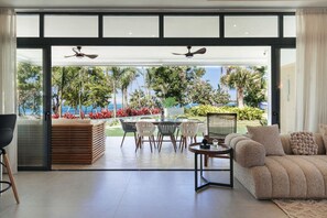 An open-plan living area with a view of the sea, a dining set, and a sofa. - 2BR Coastal Stay w/ Ocean View | Sol de Arena F3 (Las Terrenas)