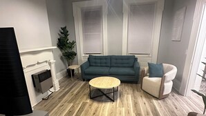 Un salon comprenant un canapé, un fauteuil, une table basse, un téléviseur et une cheminée.