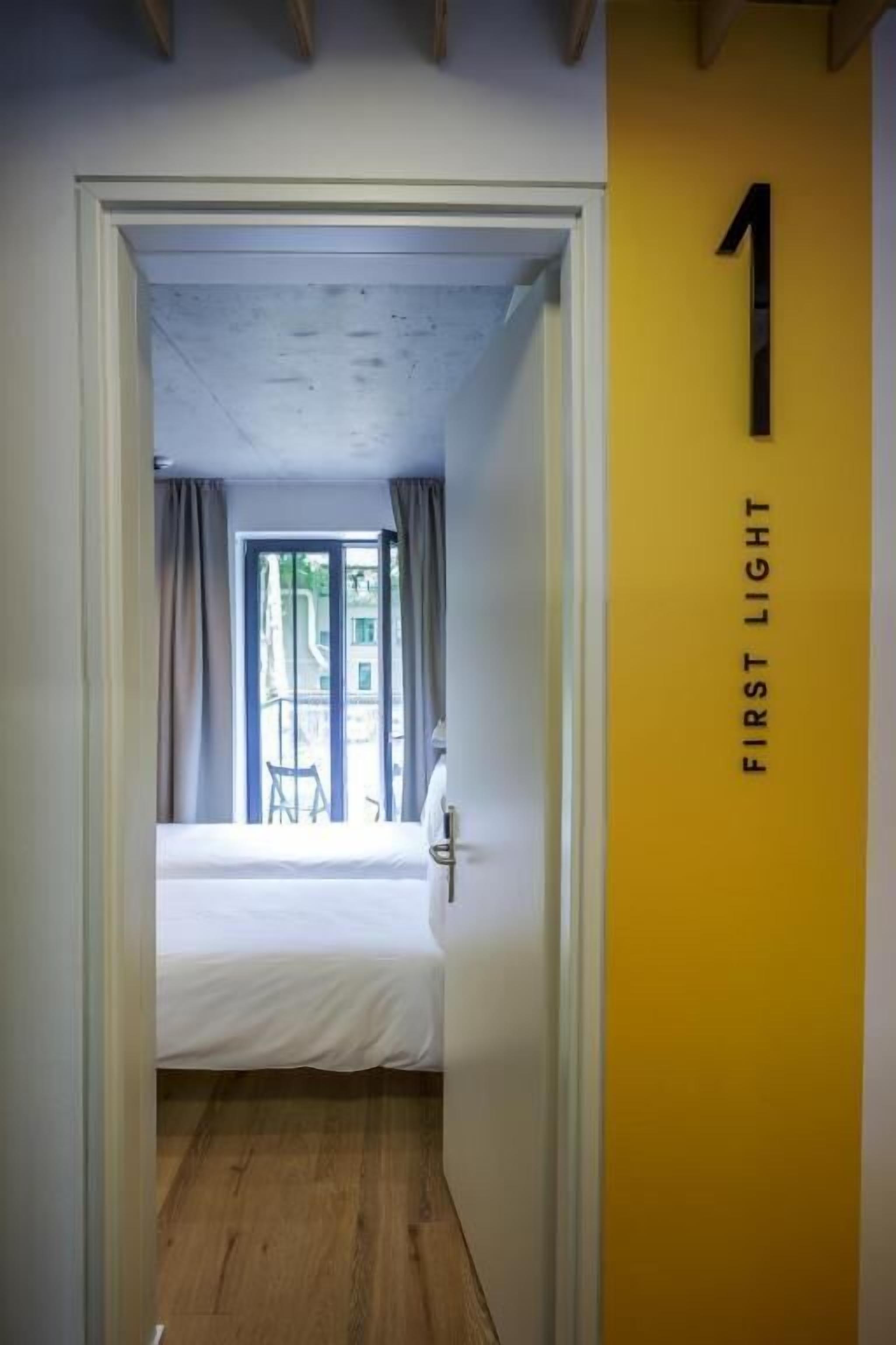 Una habitación con una cama, una ventana con cortinas y una puerta con el número 1.