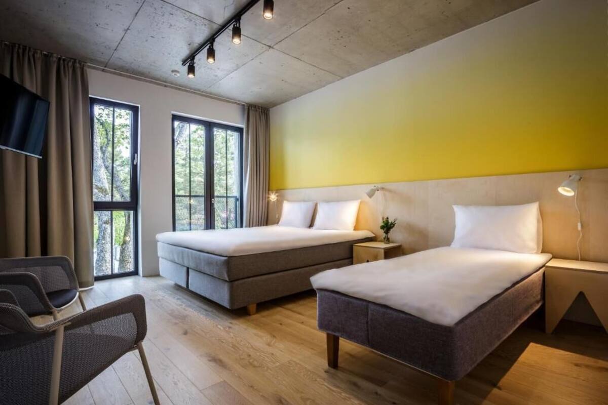 Una habitación de hotel con dos camas, un sofá, un escritorio y una silla.