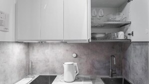 A modern kitchen with a built-in dishwasher, a kettle, a sink, and a wine rack.