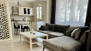 Een moderne woonkamer met een bank, een salontafel en een eethoek met stoelen en een tafel.
