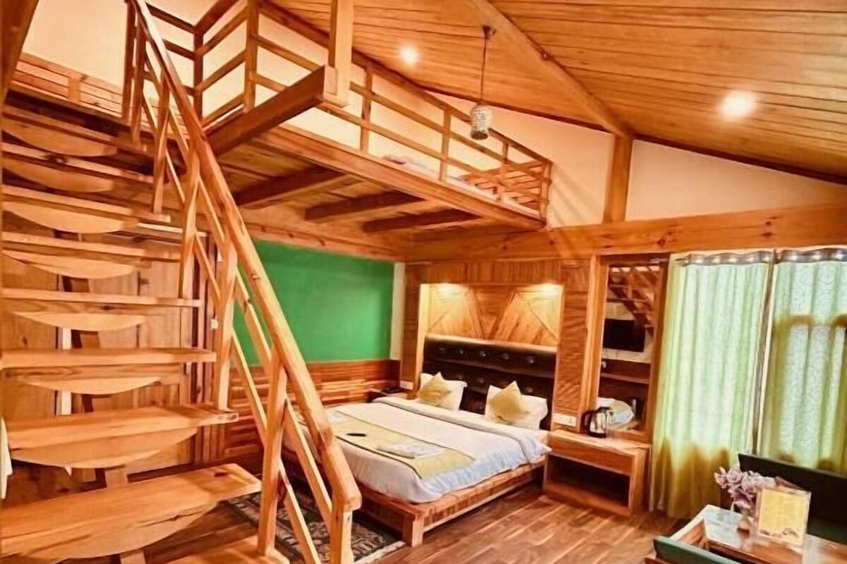 A wooden interior with a bunk bed, a staircase, and a desk.