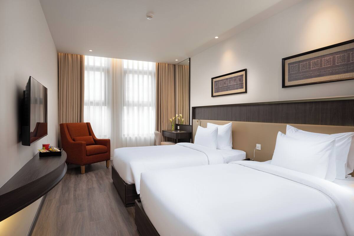Una habitación de hotel con dos camas, televisión, escritorio y una silla.