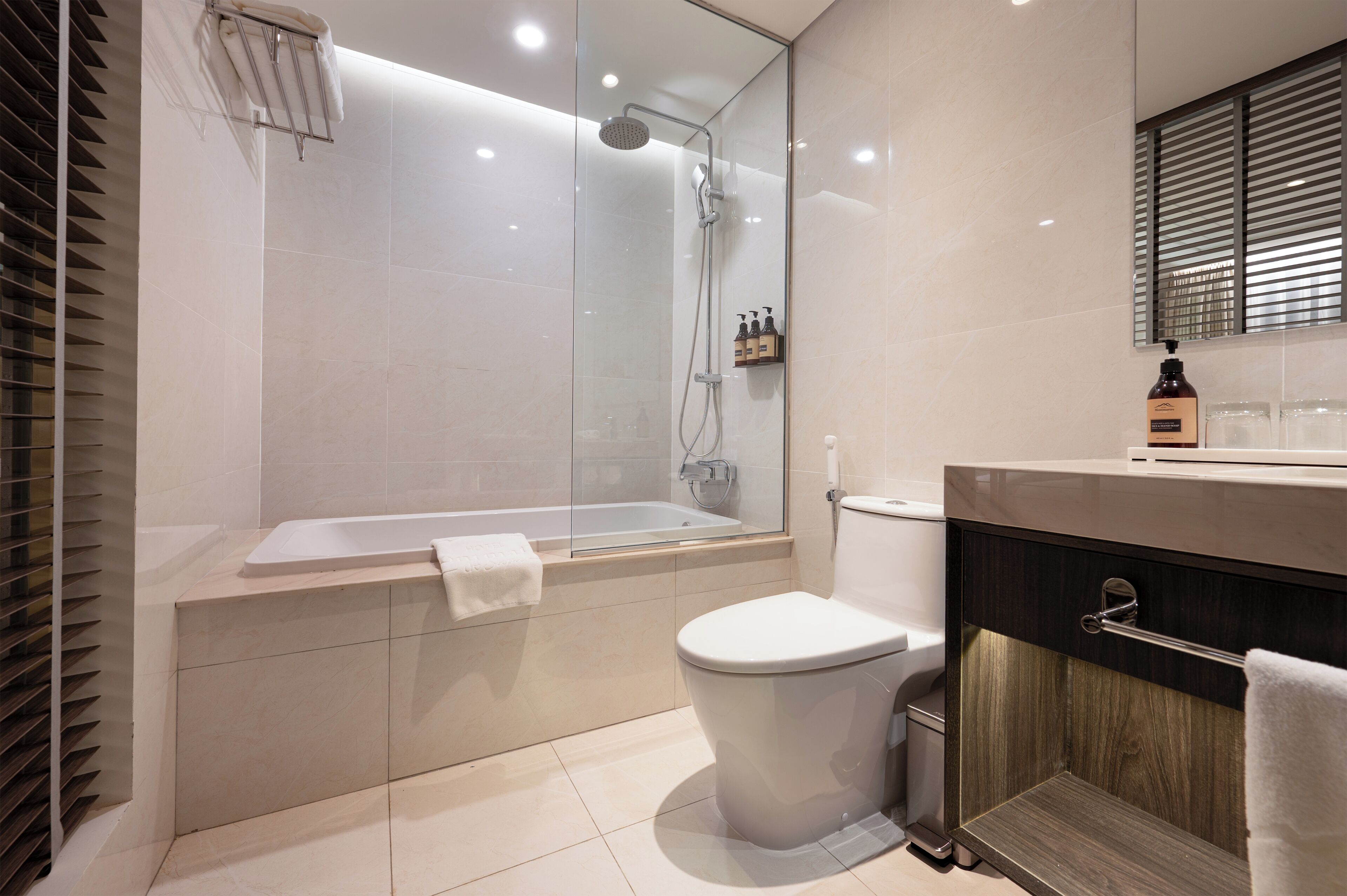 A modern bathroom with a glass-enclosed shower, a bathtub, a toilet, and a vanity with a mirror.