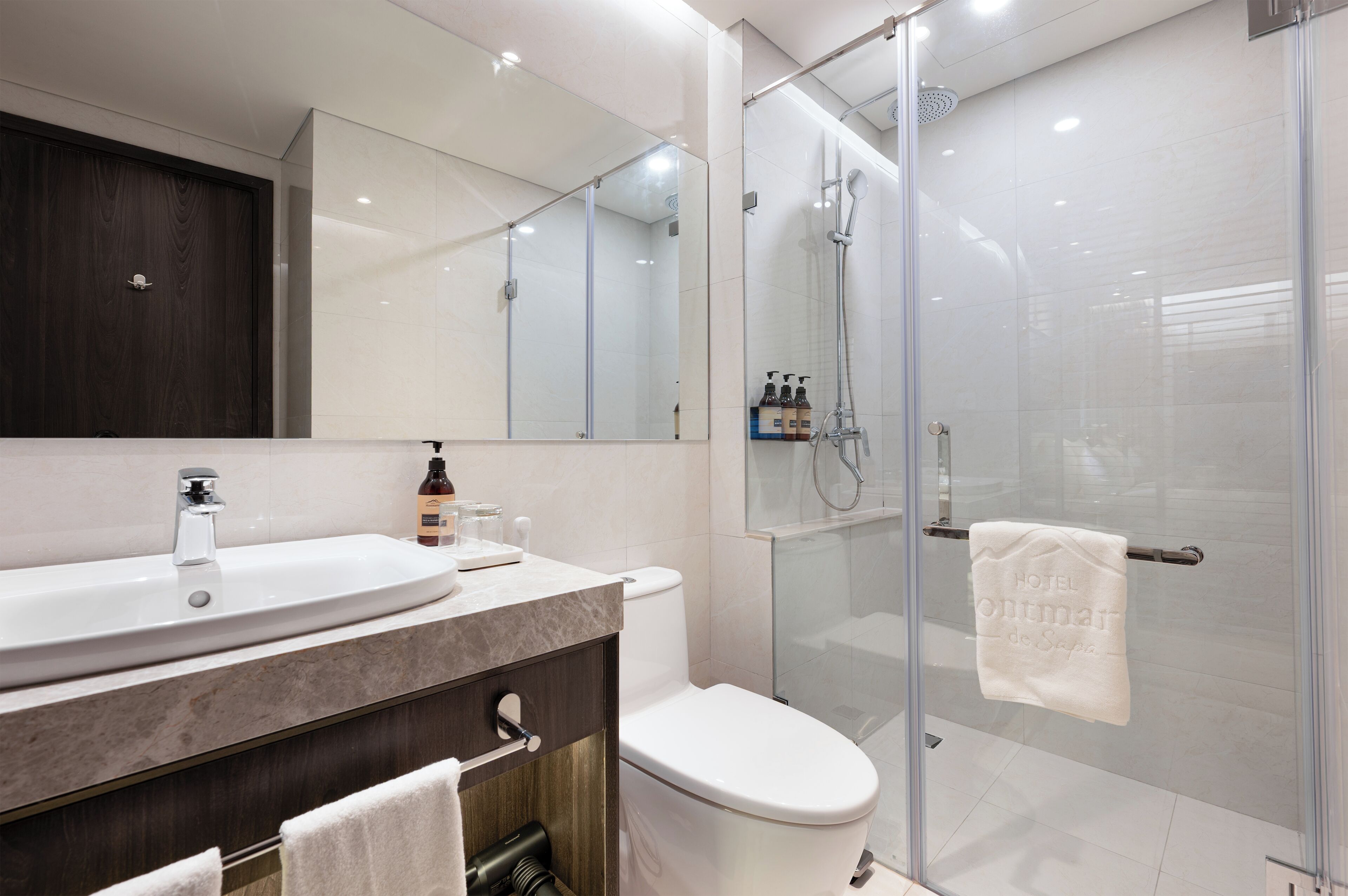 A modern bathroom with a large sink, toilet, and glass-enclosed shower.