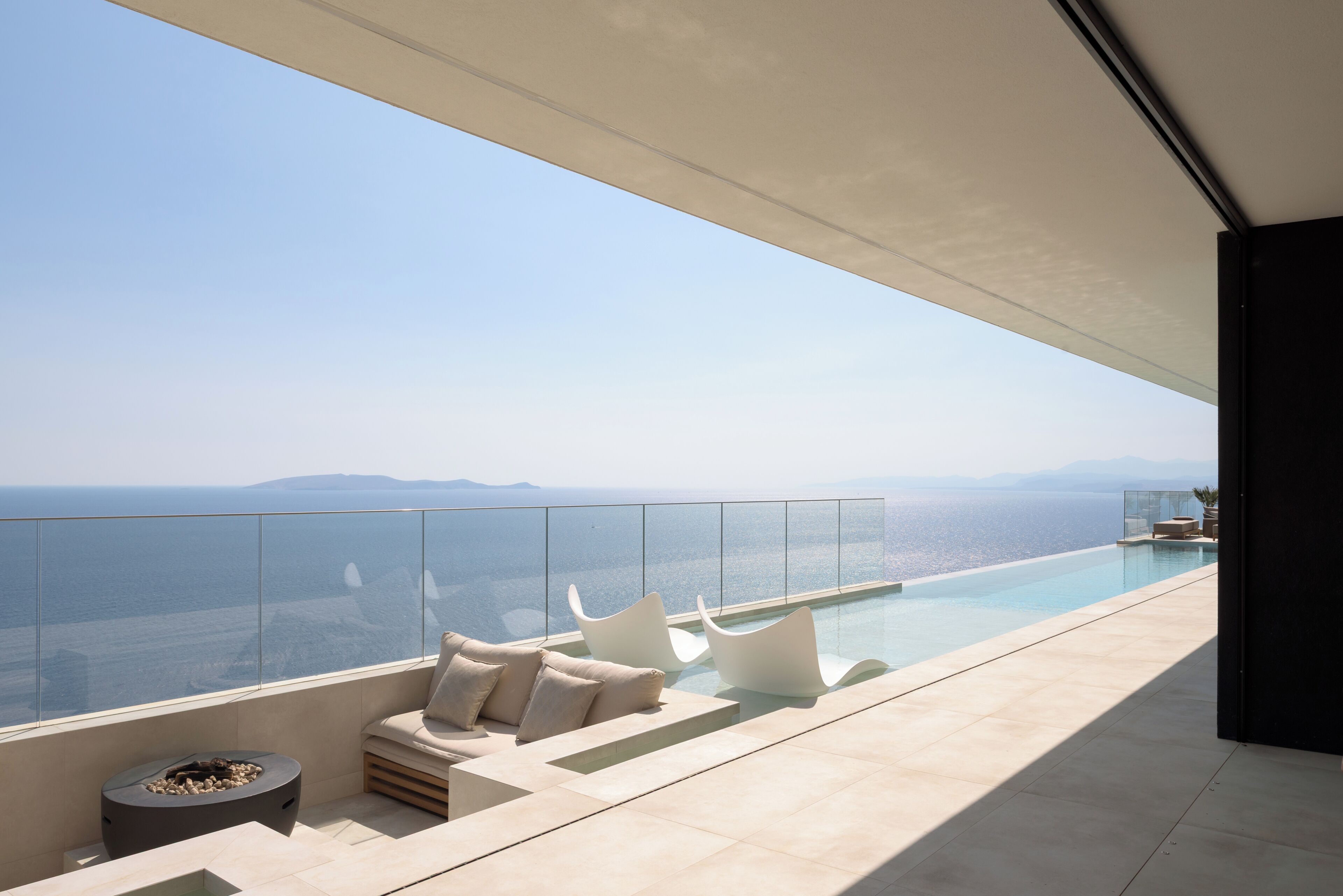 Ein moderner Infinity-Pool mit freiem Blick auf das Meer und entfernte Berge.