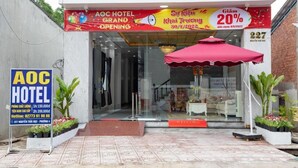 Entrada do Hotel AOC com um guarda-chuva vermelho, uma placa e uma porta de vidro.