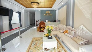 Um saguão de hotel com uma mesa de recepção, um sofá, uma mesa de centro e um candelabro.
