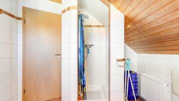 A bathroom with a shower, a bathtub, a wooden ceiling, and a white radiator.